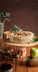 Napoleon cake on a wooden cake plate and a wooden table. Green apple and nuts