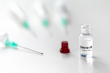 Open Coronavirus COVID-19 vaccine and injection syringe on table