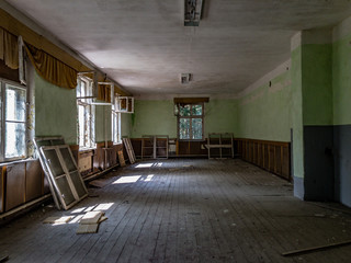 An abandoned room with broken windows and sunlight coming in through the left side