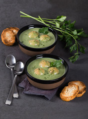 Cream-soup greens with croutons in a bowl on a dark background top view