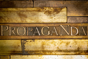 Photo of real authentic typeset letters forming Propaganda text on vintage textured grunge copper background
