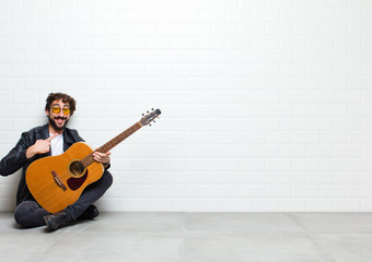 young cool musician man sitting on the floor with a guitar