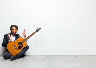 young cool musician man sitting on the floor with a guitar