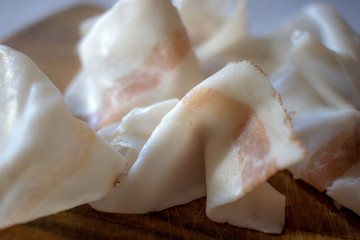 Italian Colonnata lard thinly sliced and laid on a wooden tray.