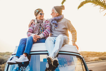 Couple of old senior traveler sit down  together on the roof of the van enjoy the sunset time together with love - forever and vacation concept for traveler retired people