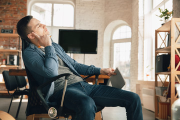 Creative workplace - organized work space as you like for inspiration. Man working in office in comfortable attire, relaxed position and messy table. Choose atmosphere you want - ideal clear or chaos.