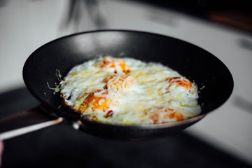 Fried eggs sprinkled with cheese lie in a hot pan