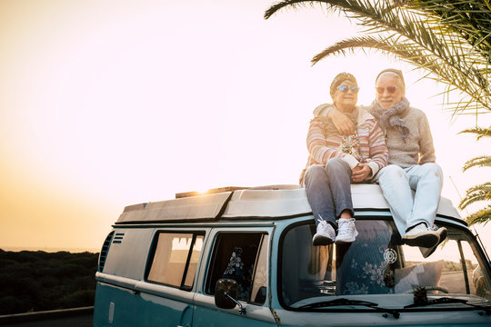 Couple of old senior traveler sit down  together on the roof of the van enjoy the sunset time together with love - forever and vacation concept for traveler retired people