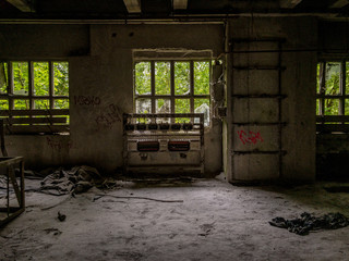 Electrical installations in an abandoned factory, broken windows and overgrown forest outside the room