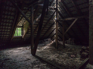 An old loft and roof interior, wooden beams and dusty floor in an abandoned building
