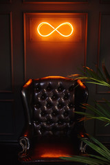 Neon glowing sign with infinity and green wall
