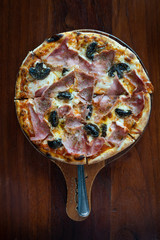 pizza with ham and mushrooms on a wooden board