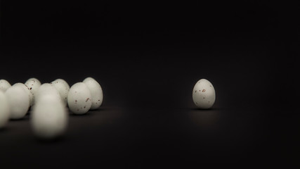 Einsames Wachtelei getrennt von Gruppe vor schwarzem Hintergrund. Lonely quail egg separated from group on black background.