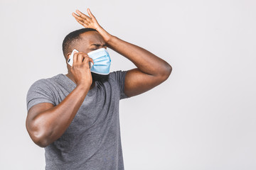 Shocked young african american man in sterile face mask posing isolated on white wall background....