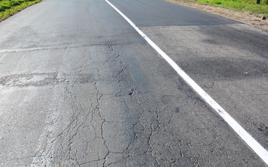 Rural asphalt road damage, heavy trucks cause cracks on roads and ruin roads.