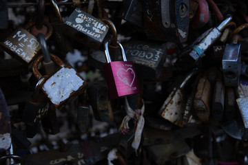 Padlocks of love on a bridge with a central pink padlock with a heart on it