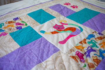 A handmade patchwork quilt repeating square pattern with the image of cat in the middle