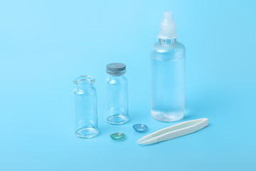 Contact lenses, solution and tweezers on color background