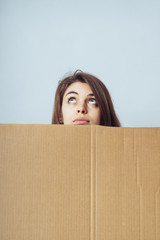 girl looks out from behind a cardboard paper