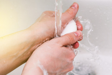 Hand of a man with soap under the tap with water close-up. Hygiene rules and prevention of coronavirus. Hand washing from dirt and infections.