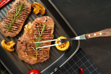 Beef steaks with vegetables on grill pan, top view