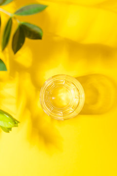 Top View Of Glass With Water On Yellow Surface With Shadow