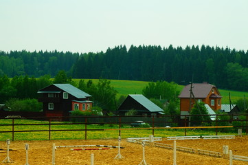 country houses on the background of the forest. near the horse corral