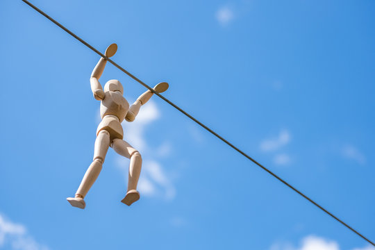 boneco manequim de madeira articulado pendurado na corda com c&eacute;u azul