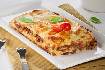 lasagna with vegetables in a plate on a white background