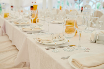 Table set with sparkling wineglasses, plates with serviette and cutlery on table, copy space. Place setting at wedding reception. Table served for wedding banquet in restaurant