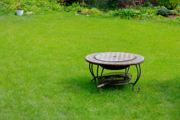A stylish barbecue grill stands in the middle of the courtyard or garden on the green lawn grass. Copyspace.