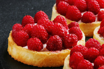 raspberries tart on the table. Fruit raspberry tart cakes on a black table.