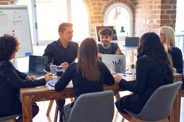 Group of business workers smiling happy and confident. Working together with smile on face  using laptop and speaking at the office