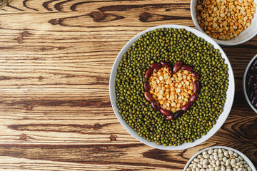 Assortment of beans on wooden background.