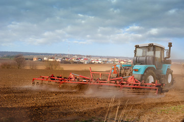 Fototapeta premium Farmers prepare the plowded land , tractor with a seeder, sowing time
