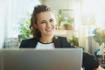 smiling stylish woman using website while sitting on couch