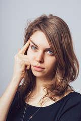 long-haired beautiful young brunette woman holding a finger to his temple, ready to shoot