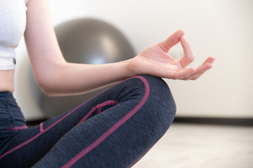 Young sporty woman practicing yoga lesson sitting in Sukhasana exercise, Easy Seat pose with mudra...