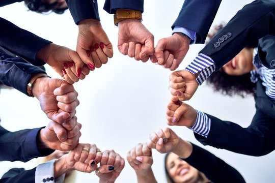 Group of business workers standing bumping fists at the office