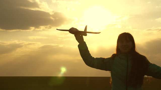 girl wants to become pilot and an astronaut. Free girl runs with a toy airplane on field in sunset light. healthy children play toy airplane. teenager dreams of flying and becoming pilot. Slow motion