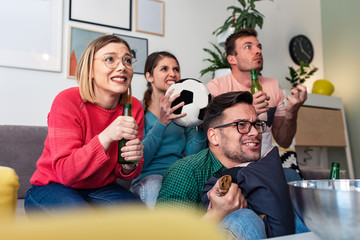 Cheerful friends watching soccer match at home and cheering for their team.