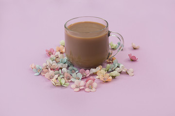 Cup of coffee on a pink background with flowers.