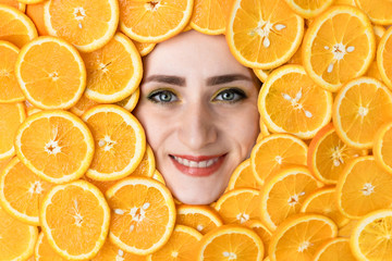 The face of a smiling girl among sliced oranges. Vitamin C. orange in the section.