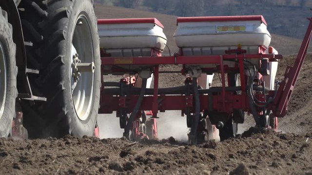 Tractor working in a field. Tractor with a seeder, sow crops at field. Sowing agricultural crops. Tractor with a seeder to sowing in a huge field. Agricultural work. Spring sowing