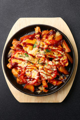 frying pan with potatoes meat and tomatoes on black concrete background. mexican food concept. potatoes fried in a pan
