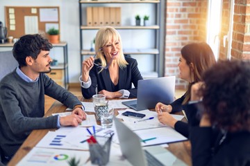 Group of business workers smiling happy and confident. Working together with smile on face  using laptop and speaking at the office