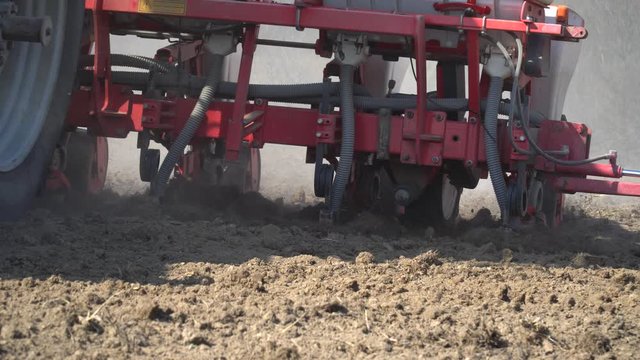 Tractor working in a field. Tractor with a seeder, sow crops at field. Sowing agricultural crops. Tractor with a seeder to sowing in a huge field. Agricultural work. Spring sowing