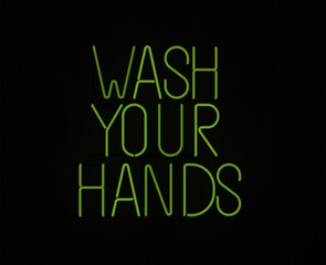 Wash your Hands in neon lettering against black backdrop important advice for covid 19 pandemic