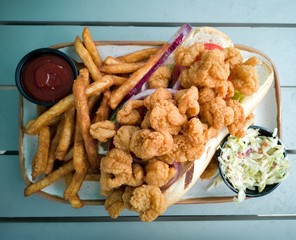 Po-Boy sandwich with fried shrimps, French fries and coleslaw. Top down.