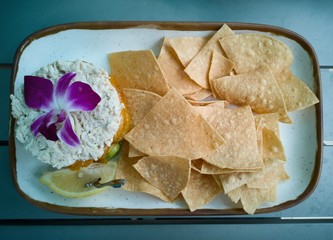 Crab cake served with edible flower, lime and a side of corn chips.